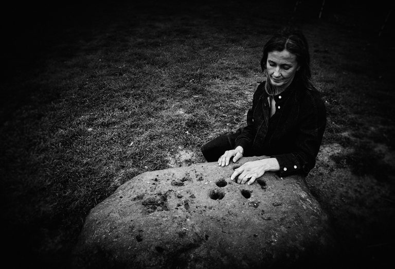 Joanne Burn photographed with the boundary stone in Eyam